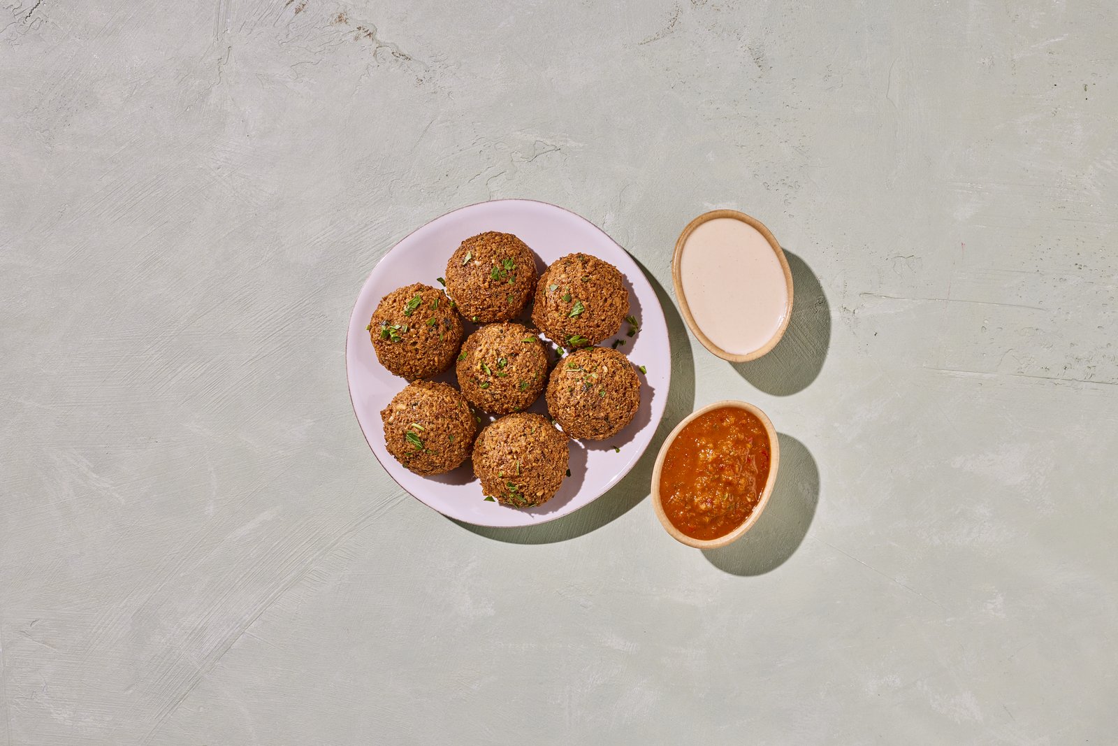 Six golden falafel with tahini and spicy tomato dipping sauces