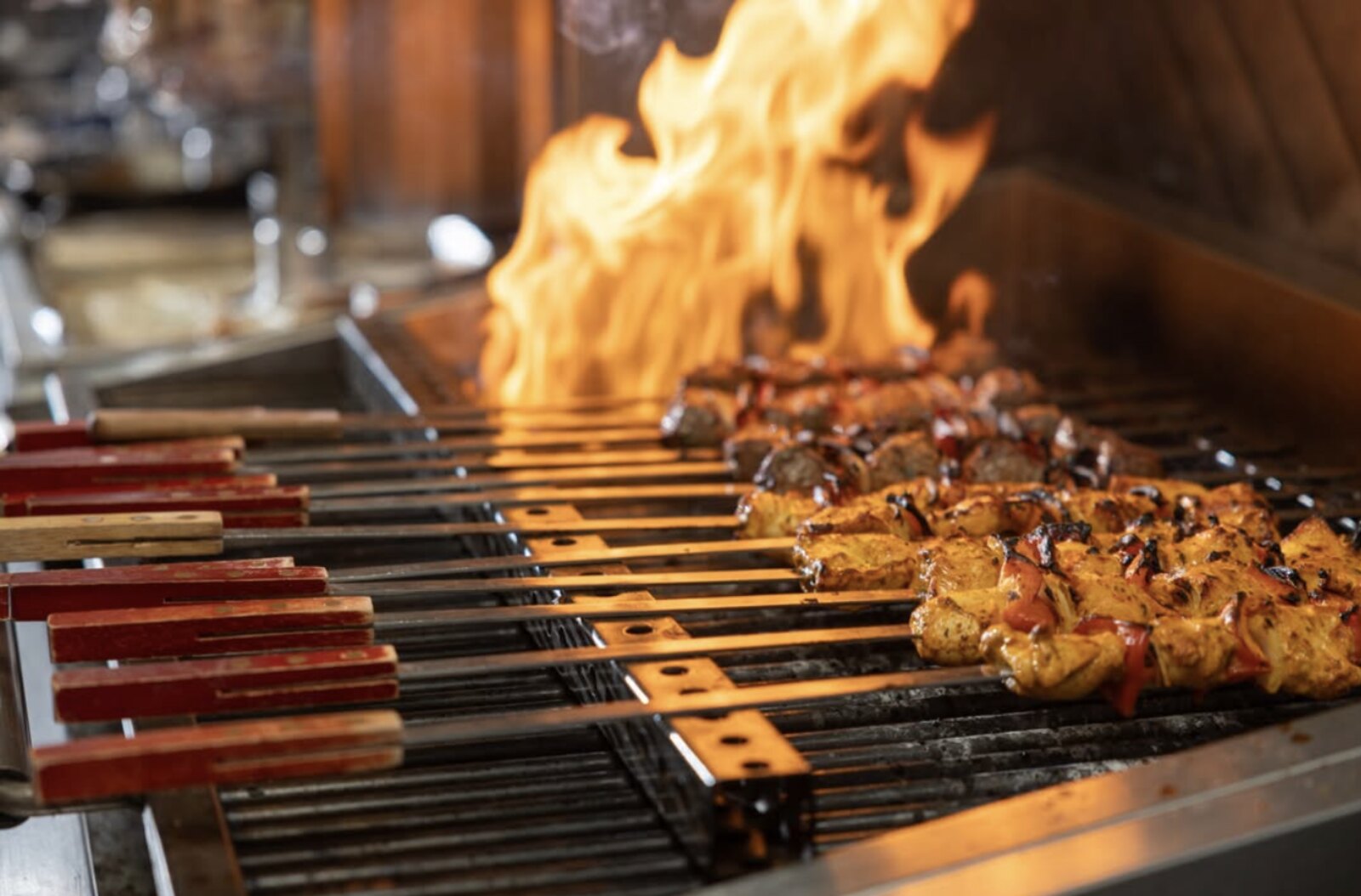 Chicken and kafta kabobs char-grilling over open flame on the Sinya grill