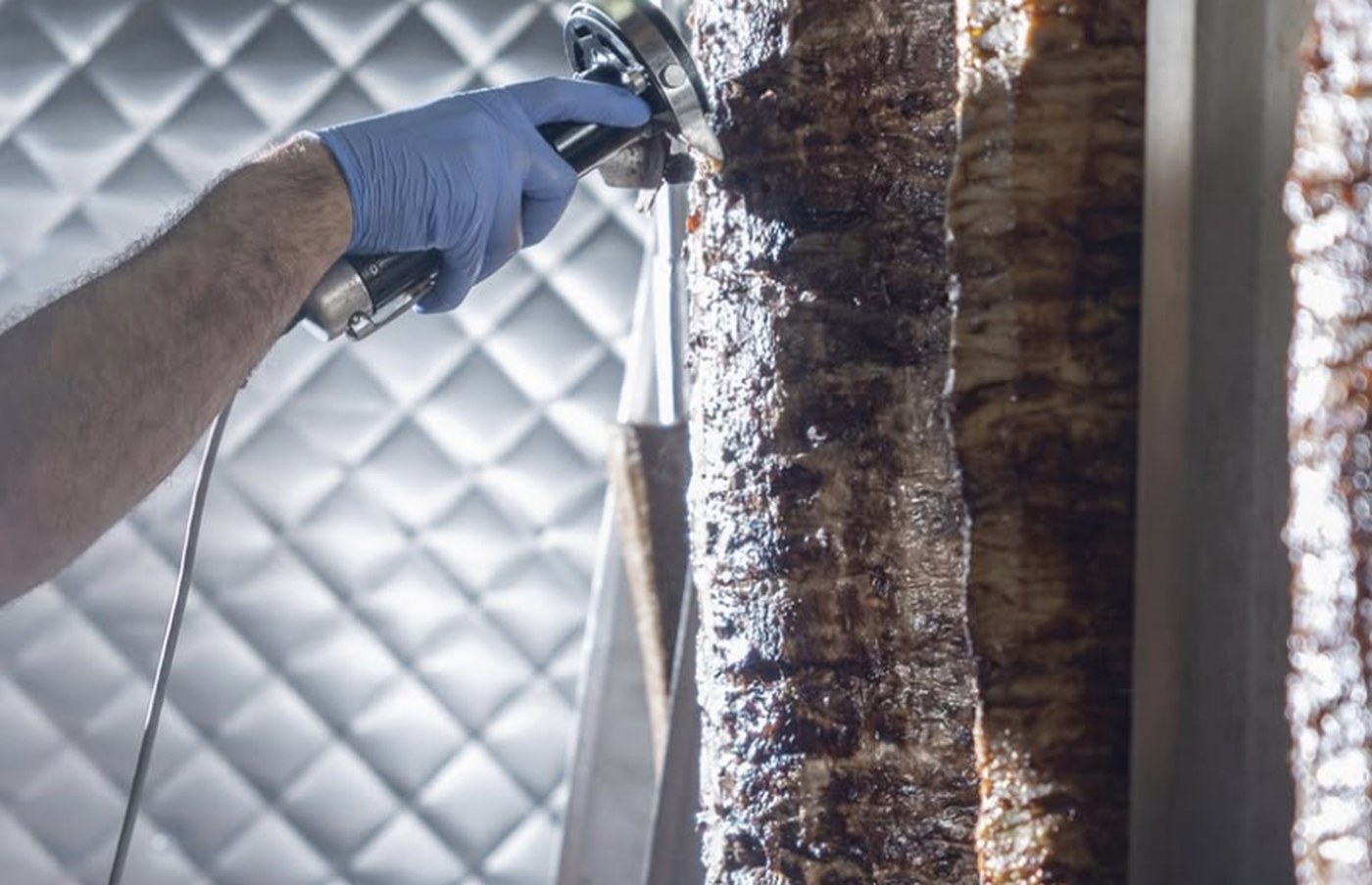 A Sinya cook carving shawarma from the vertical spit